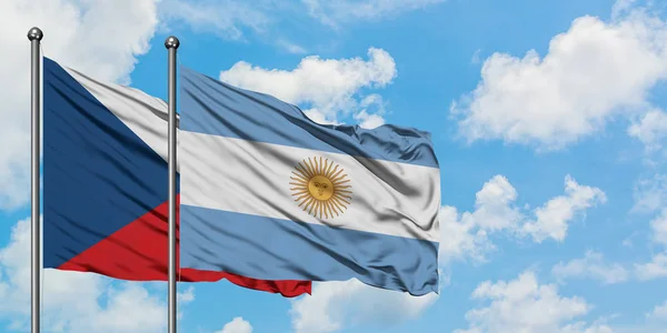 Bandera de República Checa y Argentina ondeando en el viento contra el cielo azul nublado blanco juntos. Concepto diplomático, relaciones internacionales . — Foto de Stock