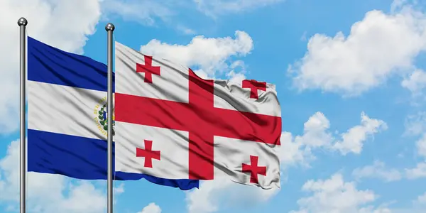 El Salvador och Georgien flagga vinka i vinden mot vit grumlig blå himmel tillsammans. Diplomatisk koncept, internationella relationer. — Stockfoto