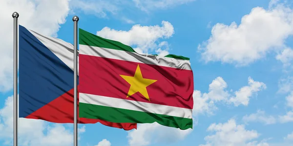 Bandera de República Checa y Surinam ondeando en el viento contra el cielo azul nublado blanco juntos. Concepto diplomático, relaciones internacionales . — Foto de Stock