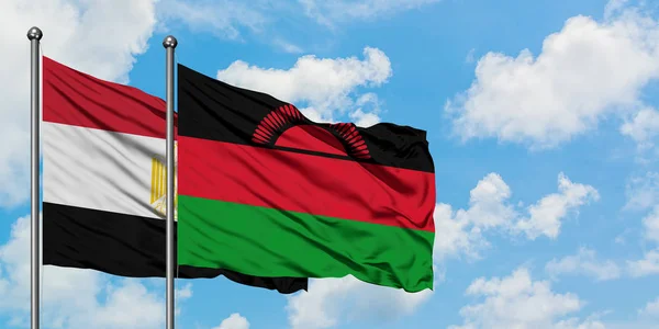 Bandera de Egipto y Malawi ondeando en el viento contra el cielo azul nublado blanco juntos. Concepto diplomático, relaciones internacionales . — Foto de Stock