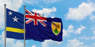 Curacao ve Turks ve Caicos Adaları bayrağı birlikte beyaz bulutlu mavi gökyüzüne karşı rüzgarda sallayarak. Diplomasi kavramı, uluslararası ilişkiler.