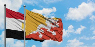 Mısır ve Butan bayrağı birlikte beyaz bulutlu mavi gökyüzüne karşı rüzgarda sallayarak. Diplomasi kavramı, uluslararası ilişkiler.