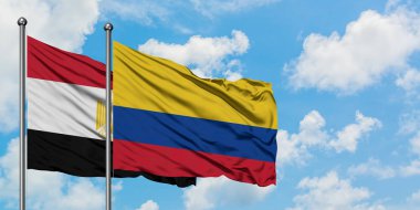 Mısır ve Kolombiya bayrağı birlikte beyaz bulutlu mavi gökyüzüne karşı rüzgarda sallayarak. Diplomasi kavramı, uluslararası ilişkiler.