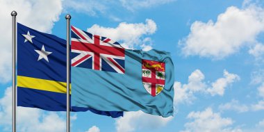 Curacao ve Fiji bayrağı birlikte beyaz bulutlu mavi gökyüzüne karşı rüzgarda sallayarak. Diplomasi kavramı, uluslararası ilişkiler.