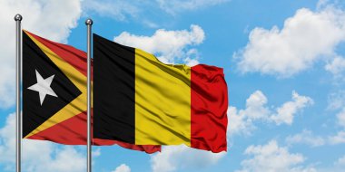 Doğu Timor ve Belçika bayrağı birlikte beyaz bulutlu mavi gökyüzüne karşı rüzgarsal sallayarak. Diplomasi kavramı, uluslararası ilişkiler.