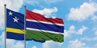 Curacao ve Gambiya bayrağı birlikte beyaz bulutlu mavi gökyüzüne karşı rüzgarda sallayarak. Diplomasi kavramı, uluslararası ilişkiler.