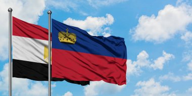 Mısır ve Lihtenştayn bayrağı birlikte beyaz bulutlu mavi gökyüzüne karşı rüzgarda sallayarak. Diplomasi kavramı, uluslararası ilişkiler.