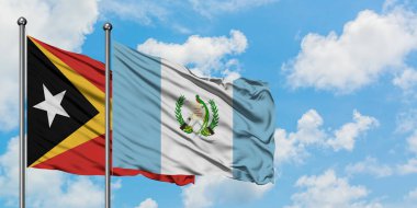 Doğu Timor ve Guatemala bayrağı birlikte beyaz bulutlu mavi gökyüzüne karşı rüzgarda sallayarak. Diplomasi kavramı, uluslararası ilişkiler.