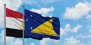 Mısır ve Tokelau bayrağı birlikte beyaz bulutlu mavi gökyüzüne karşı rüzgarda sallayarak. Diplomasi kavramı, uluslararası ilişkiler.