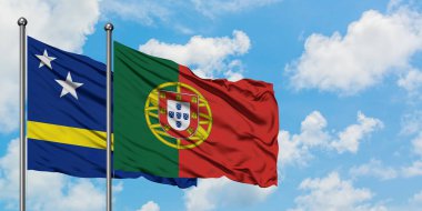 Curacao ve Portekiz bayrağı birlikte beyaz bulutlu mavi gökyüzüne karşı rüzgarda sallayarak. Diplomasi kavramı, uluslararası ilişkiler.