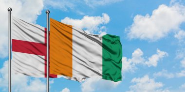 İngiltere ve Fildişi Sahili bayrağı birlikte beyaz bulutlu mavi gökyüzüne karşı rüzgarda sallayarak. Diplomasi kavramı, uluslararası ilişkiler.