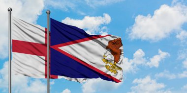 İngiltere ve Amerikan Samoası bayrağı birlikte beyaz bulutlu mavi gökyüzüne karşı rüzgarda sallayarak. Diplomasi kavramı, uluslararası ilişkiler.