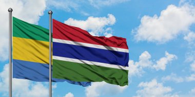 Gabon ve Gambiya bayrağı birlikte beyaz bulutlu mavi gökyüzüne karşı rüzgarda sallayarak. Diplomasi kavramı, uluslararası ilişkiler.