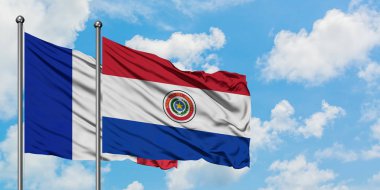 Fransa ve Paraguay bayrağı birlikte beyaz bulutlu mavi gökyüzüne karşı rüzgarda sallayarak. Diplomasi kavramı, uluslararası ilişkiler.