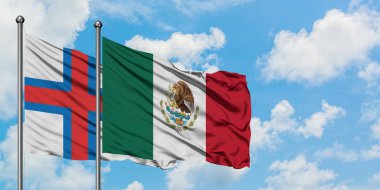 Faroe Adaları ve Meksika bayrağı birlikte beyaz bulutlu mavi gökyüzüne karşı rüzgarda sallayarak. Diplomasi kavramı, uluslararası ilişkiler.