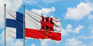 Finlandiya ve Cebelitarık bayrağı birlikte beyaz bulutlu mavi gökyüzüne karşı rüzgarsal sallayarak. Diplomasi kavramı, uluslararası ilişkiler.