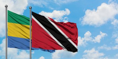 Gabon ve Trinidad ve Tobago bayrağı birlikte beyaz bulutlu mavi gökyüzüne karşı rüzgarda sallayarak. Diplomasi kavramı, uluslararası ilişkiler.