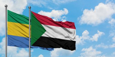 Gabon ve Sudan bayrağı birlikte beyaz bulutlu mavi gökyüzüne karşı rüzgarda sallayarak. Diplomasi kavramı, uluslararası ilişkiler.