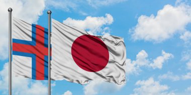 Faroe Adaları ve Japonya bayrağı birlikte beyaz bulutlu mavi gökyüzüne karşı rüzgarda sallayarak. Diplomasi kavramı, uluslararası ilişkiler.