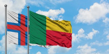 Faroe Adaları ve Benin bayrağı birlikte beyaz bulutlu mavi gökyüzüne karşı rüzgarda sallayarak. Diplomasi kavramı, uluslararası ilişkiler.