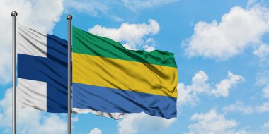 Finlandiya ve Gabon bayrağı birlikte beyaz bulutlu mavi gökyüzüne karşı rüzgarda sallayarak. Diplomasi kavramı, uluslararası ilişkiler.
