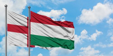 İngiltere ve Macaristan bayrağı birlikte beyaz bulutlu mavi gökyüzüne karşı rüzgarda sallayarak. Diplomasi kavramı, uluslararası ilişkiler.