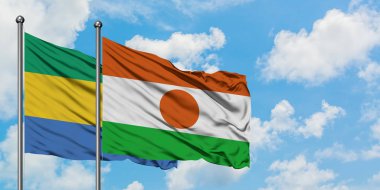 Gabon ve Nijer bayrağı birlikte beyaz bulutlu mavi gökyüzüne karşı rüzgarda sallayarak. Diplomasi kavramı, uluslararası ilişkiler.