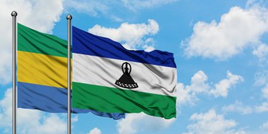 Gabon ve Lesotho bayrağı birlikte beyaz bulutlu mavi gökyüzüne karşı rüzgarda sallayarak. Diplomasi kavramı, uluslararası ilişkiler.