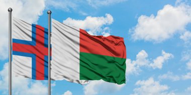 Faroe Adaları ve Madagaskar bayrağı birlikte beyaz bulutlu mavi gökyüzüne karşı rüzgarda sallayarak. Diplomasi kavramı, uluslararası ilişkiler.