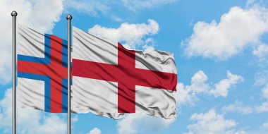 Faroe Adaları ve İngiltere bayrağı birlikte beyaz bulutlu mavi gökyüzüne karşı rüzgarda sallayarak. Diplomasi kavramı, uluslararası ilişkiler.