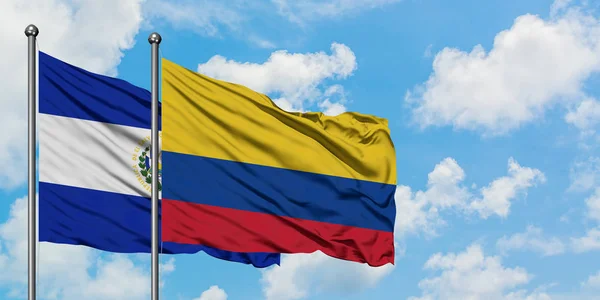 Bandera de El Salvador y Colombia ondeando en el viento contra el cielo azul nublado blanco juntos. Concepto diplomático, relaciones internacionales . — Foto de Stock