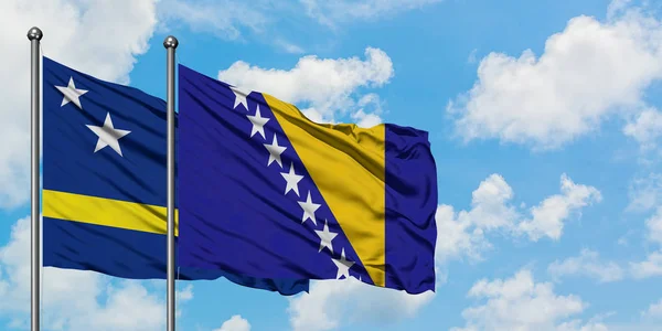 Bandera de Curazao y Bosnia Herzegovina ondeando en el viento contra el cielo azul nublado blanco juntos. Concepto diplomático, relaciones internacionales . — Foto de Stock