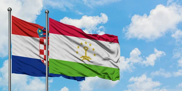 Bandera de Croacia y Tayikistán ondeando en el viento contra el cielo azul nublado blanco juntos. Concepto diplomático, relaciones internacionales . — Foto de Stock