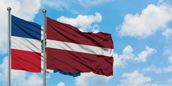 Домініканська Республіка і Латвія прапор розмахував вітром проти білого хмарного синього неба разом. Концепція дипломатії, міжнародні відносини. — стокове фото