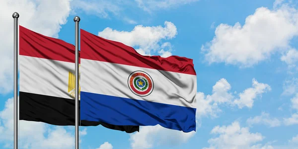 Bandera de Egipto y Paraguay ondeando en el viento contra el cielo azul nublado blanco juntos. Concepto diplomático, relaciones internacionales . — Foto de Stock