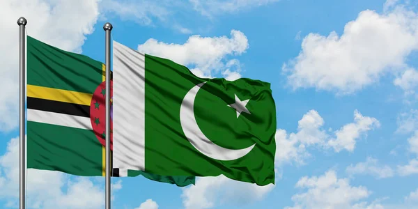 Bandera de Dominica y Pakistán ondeando en el viento contra el cielo azul nublado blanco juntos. Concepto diplomático, relaciones internacionales . — Foto de Stock