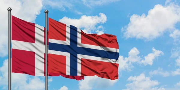 Bandera de Dinamarca y Noruega ondeando en el viento contra el cielo azul nublado blanco juntos. Concepto diplomático, relaciones internacionales . — Foto de Stock