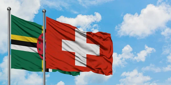 Доминика и швейцарский флаг вместе машут ветром против белого облачного голубого неба. Концепция дипломатии, международные отношения . — стоковое фото