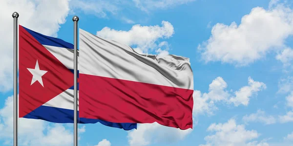 Bandera de Cuba y Polonia ondeando en el viento contra el cielo azul nublado blanco juntos. Concepto diplomático, relaciones internacionales . — Foto de Stock
