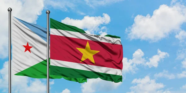 Bandera de Yibuti y Surinam ondeando en el viento contra el cielo azul nublado blanco juntos. Concepto diplomático, relaciones internacionales . — Foto de Stock