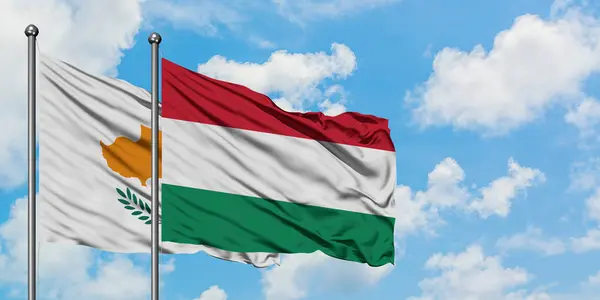 Bandera de Chipre y Hungría ondeando en el viento contra el cielo azul nublado blanco juntos. Concepto diplomático, relaciones internacionales . — Foto de Stock