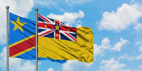 Bandera del Congo y Niue ondeando en el viento contra el cielo azul nublado blanco juntos. Concepto diplomático, relaciones internacionales . — Foto de Stock