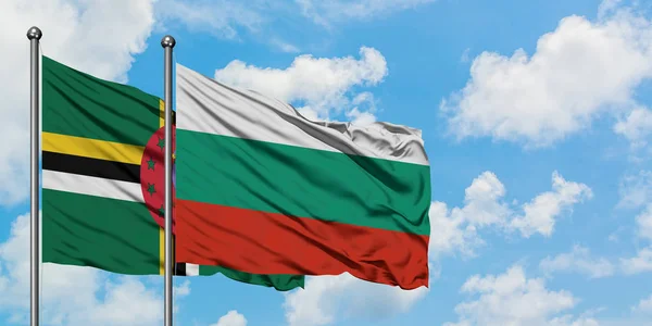 Bandera de Dominica y Bulgaria ondeando en el viento contra el cielo azul nublado blanco juntos. Concepto diplomático, relaciones internacionales . — Foto de Stock
