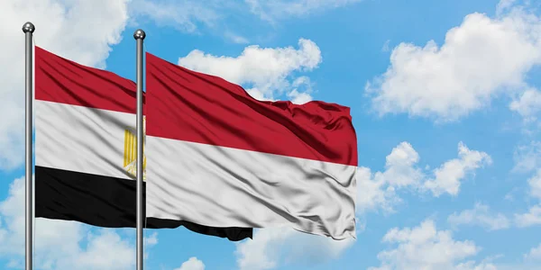 Bandera de Egipto e Indonesia ondeando en el viento contra el cielo azul nublado blanco juntos. Concepto diplomático, relaciones internacionales . — Foto de Stock