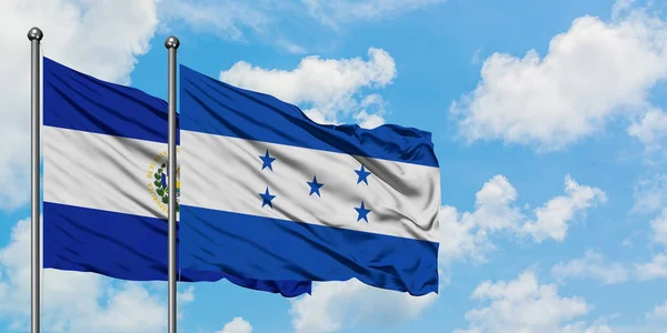 Bandera de El Salvador y Honduras ondeando en el viento contra el cielo azul nublado blanco juntos. Concepto diplomático, relaciones internacionales . — Foto de Stock