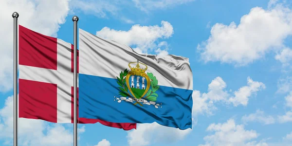 一緒に白い曇った青い空に対して風に手を振るデンマークとサンマリノの旗。外交概念、国際関係. — ストック写真