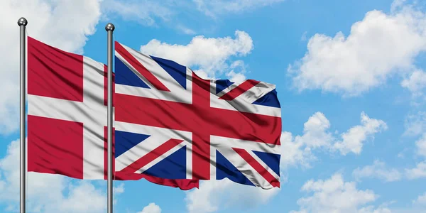 Danmark och Storbritannien sjunker vifta i vinden mot vit grumlig blå himmel tillsammans. Diplomatisk koncept, internationella relationer. — Stockfoto