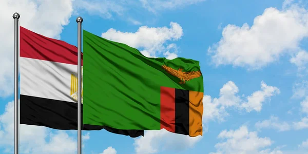 Bandera de Egipto y Zambia ondeando en el viento contra el cielo azul nublado blanco juntos. Concepto diplomático, relaciones internacionales . — Foto de Stock