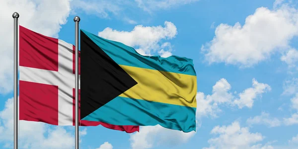 Dania i Bahamy flagi machając w wiatr przed białym zachmurzone błękitne niebo razem. Koncepcja dyplomacji, stosunki międzynarodowe. — Zdjęcie stockowe