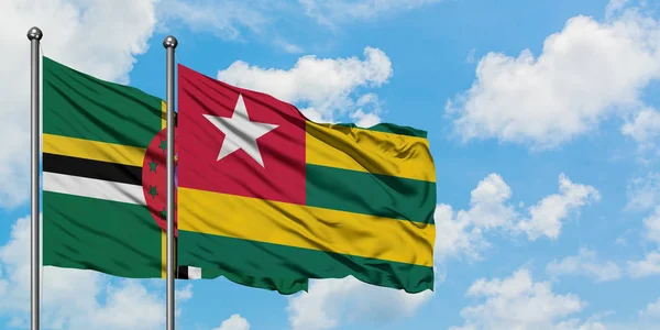 Bandera de Dominica y Togo ondeando en el viento contra el cielo azul nublado blanco juntos. Concepto diplomático, relaciones internacionales . — Foto de Stock